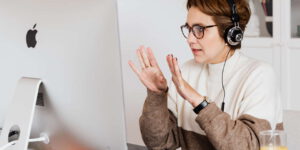 Eine Frau mit Kopfhörer vor einem PC bei einer Videokonferenz mit Microsoft Teams.