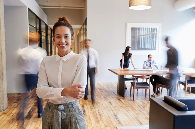 Eine junge Frau in einem sehr modernen Büro lächelt einen Besucher an. Der Besucher ist Datenschutzexperte für KMU, also für kleine und mittlere Unternehmen.