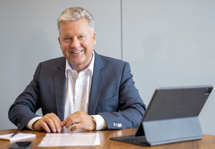 Datenschutzexperte Mannus Weiß in Hemd und Anzug sitz an seinem Schreibtisch.